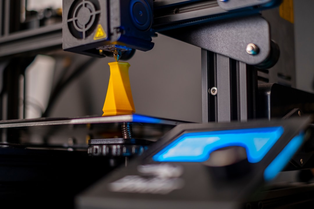 A student working on a 3D printer in a creative workspace, surrounded by printed objects and design tools.